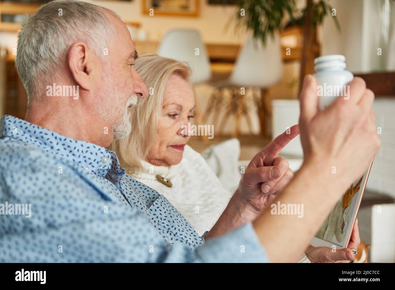 Couple senior sur une tablette informatique lors d'une consultation vidéo comme télémédecine à la maison Banque D'Images