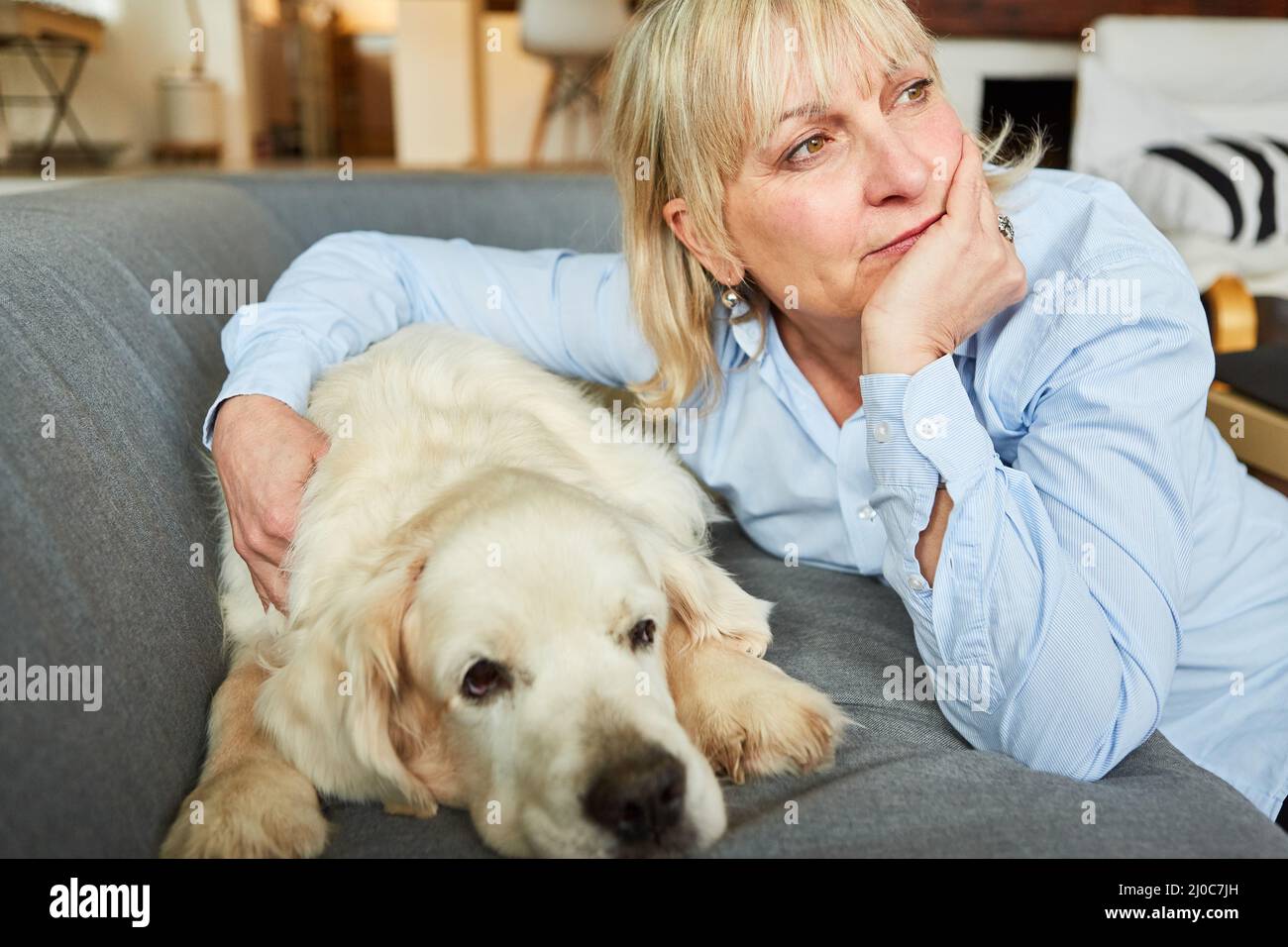 Femme âgée avec des douleurs et des soucis avec son chien de retriever sur le canapé à la maison Banque D'Images