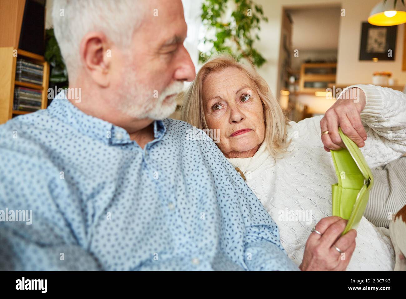 Un couple âgé inquiet avec un portefeuille vide à la maison sur un canapé comme symbole de pauvreté dans la vieillesse Banque D'Images