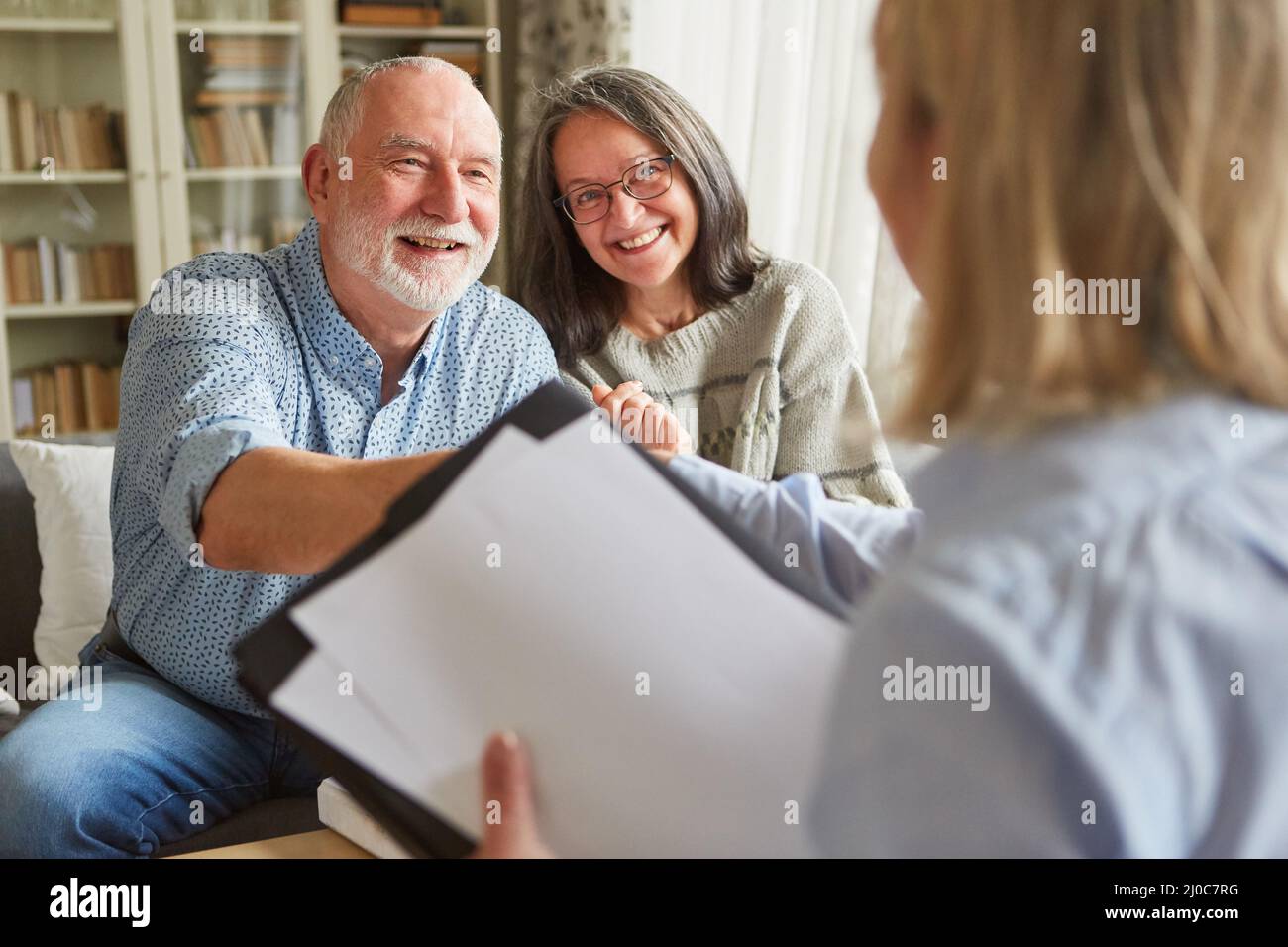 Un couple senior heureux et un conseiller se sont mis à serrer la main après la signature du contrat Banque D'Images