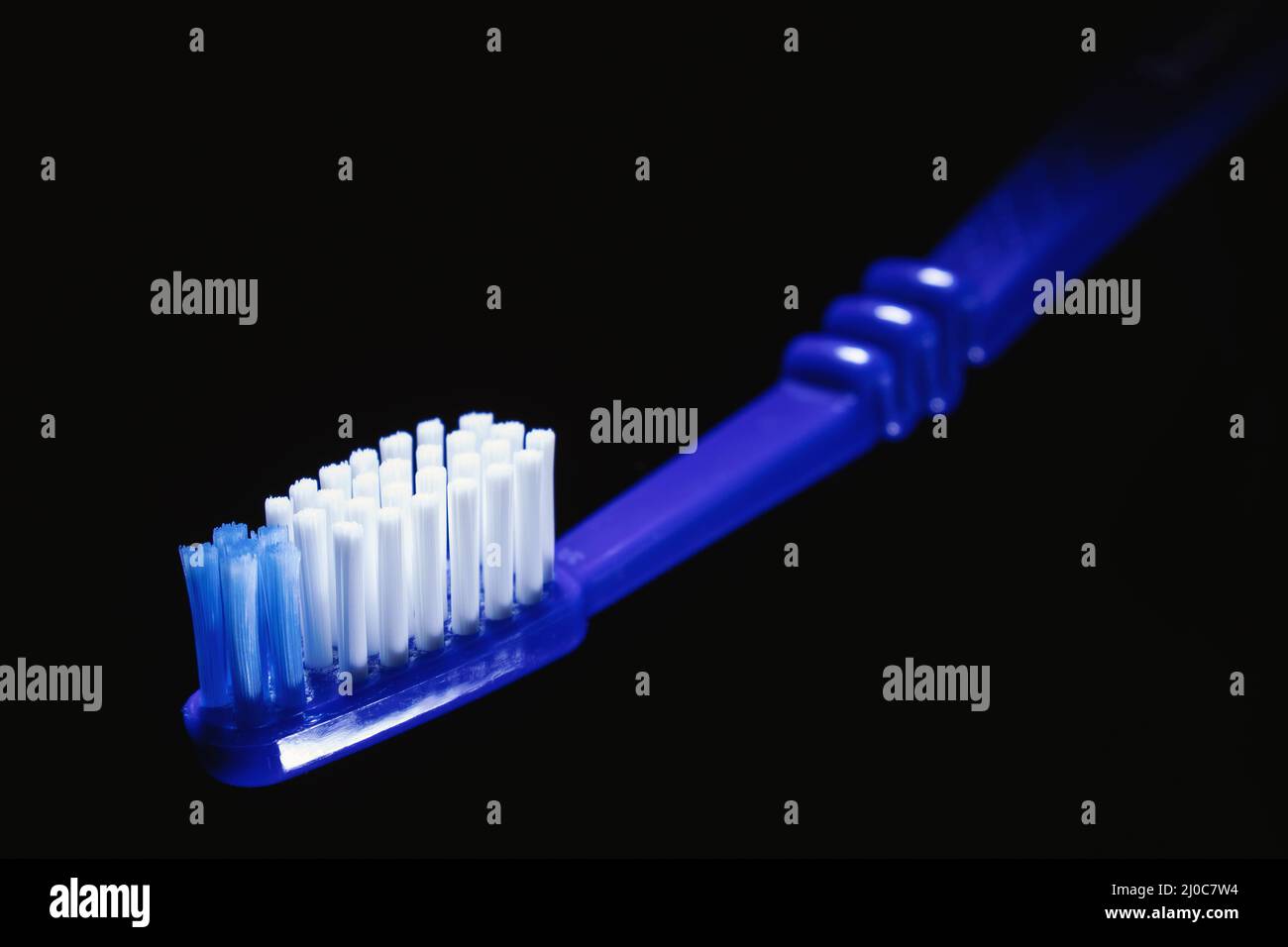 Vue en gros plan de la brosse à dents bleue sur fond noir. Banque D'Images