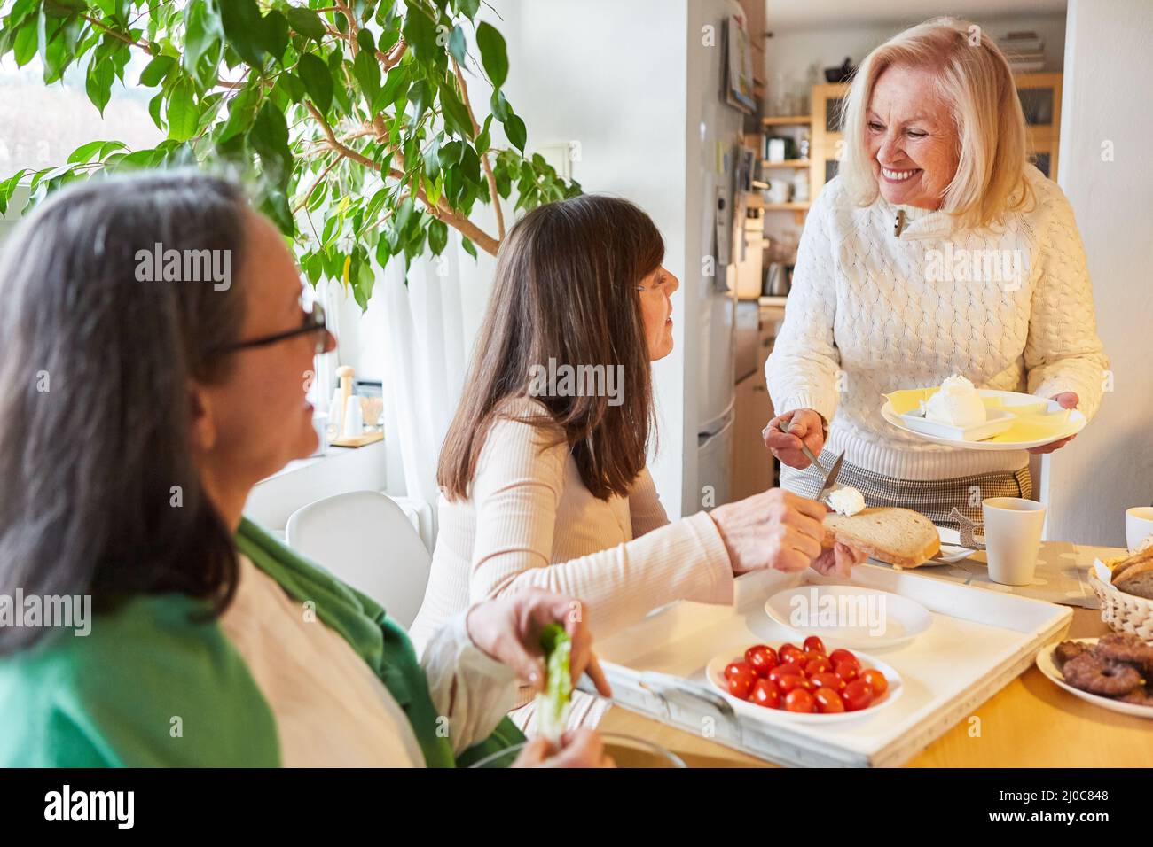 Les femmes âgées se regroupent en tant que amies et s'amusent au brunch du matin ou au petit déjeuner dans la cuisine Banque D'Images