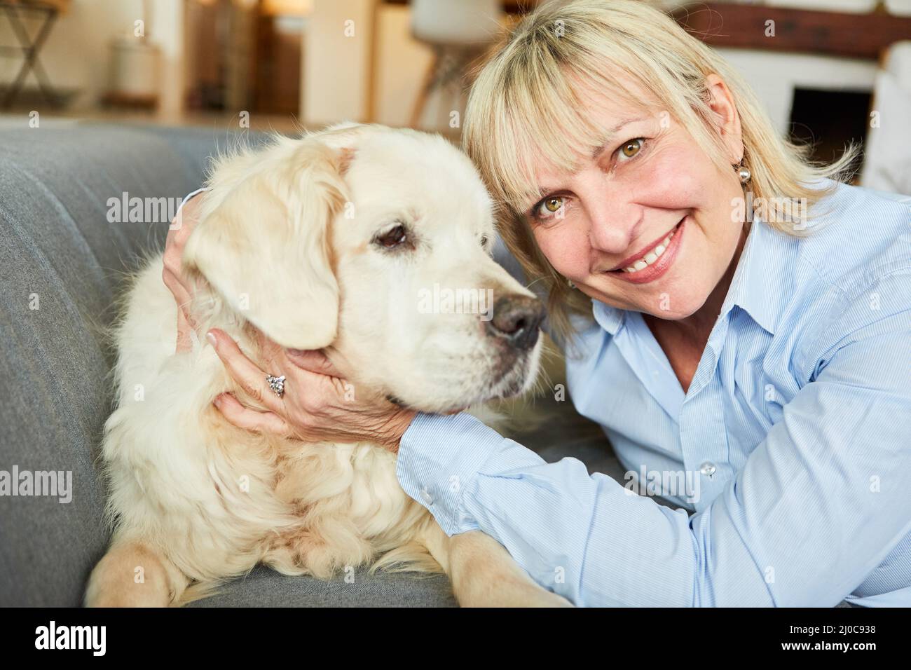 Bonne femme âgée câlin son chien de retriever pour l'amitié et la compagnie à la maison Banque D'Images