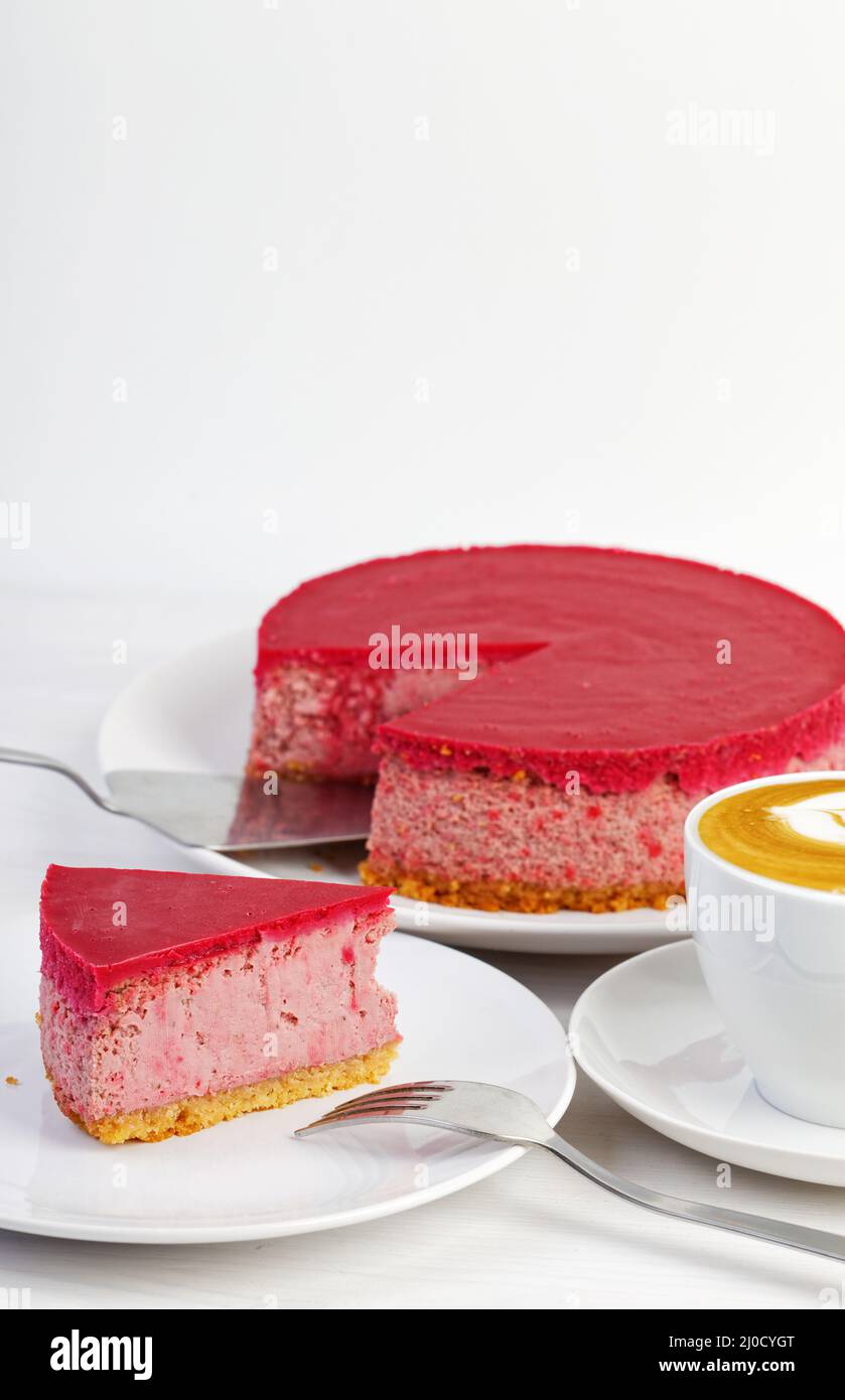 Cheesecake maison à la framboise et aux fraises et une tasse de cappuccino au café sur une table en bois blanc. CopySpace. Banque D'Images Cheesecake maison à la framboise et aux fraises et une tasse de cappuccino au café sur une table en bois blanc. CopySpace. Banque D'Images