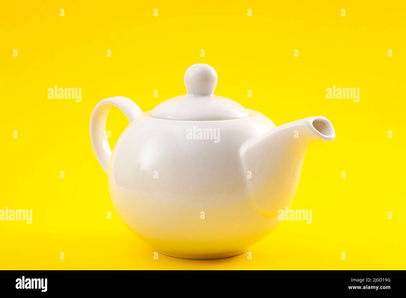 Théière en céramique blanche, cafetière ou bouilloire à thé isolée sur fond jaune Banque D'Images