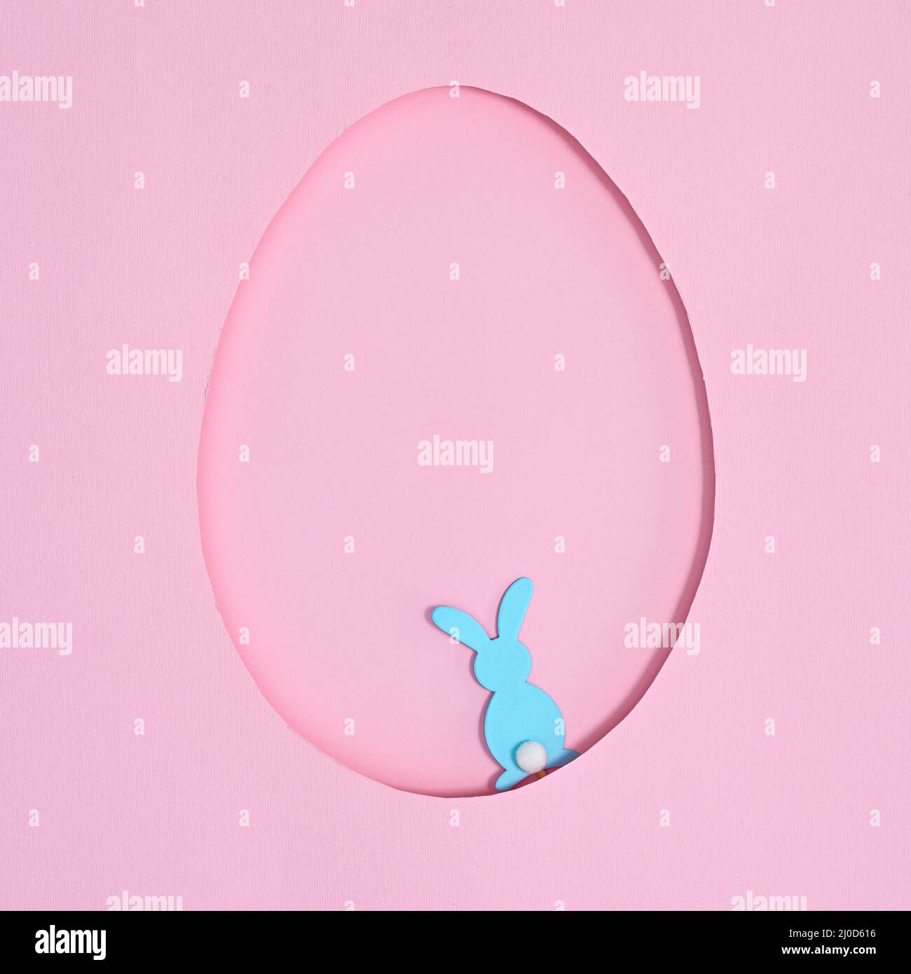 Cadre en forme d'œuf avec un lapin bleu sur fond rose pastel. Flat Lay Creative Easter concept Banque D'Images