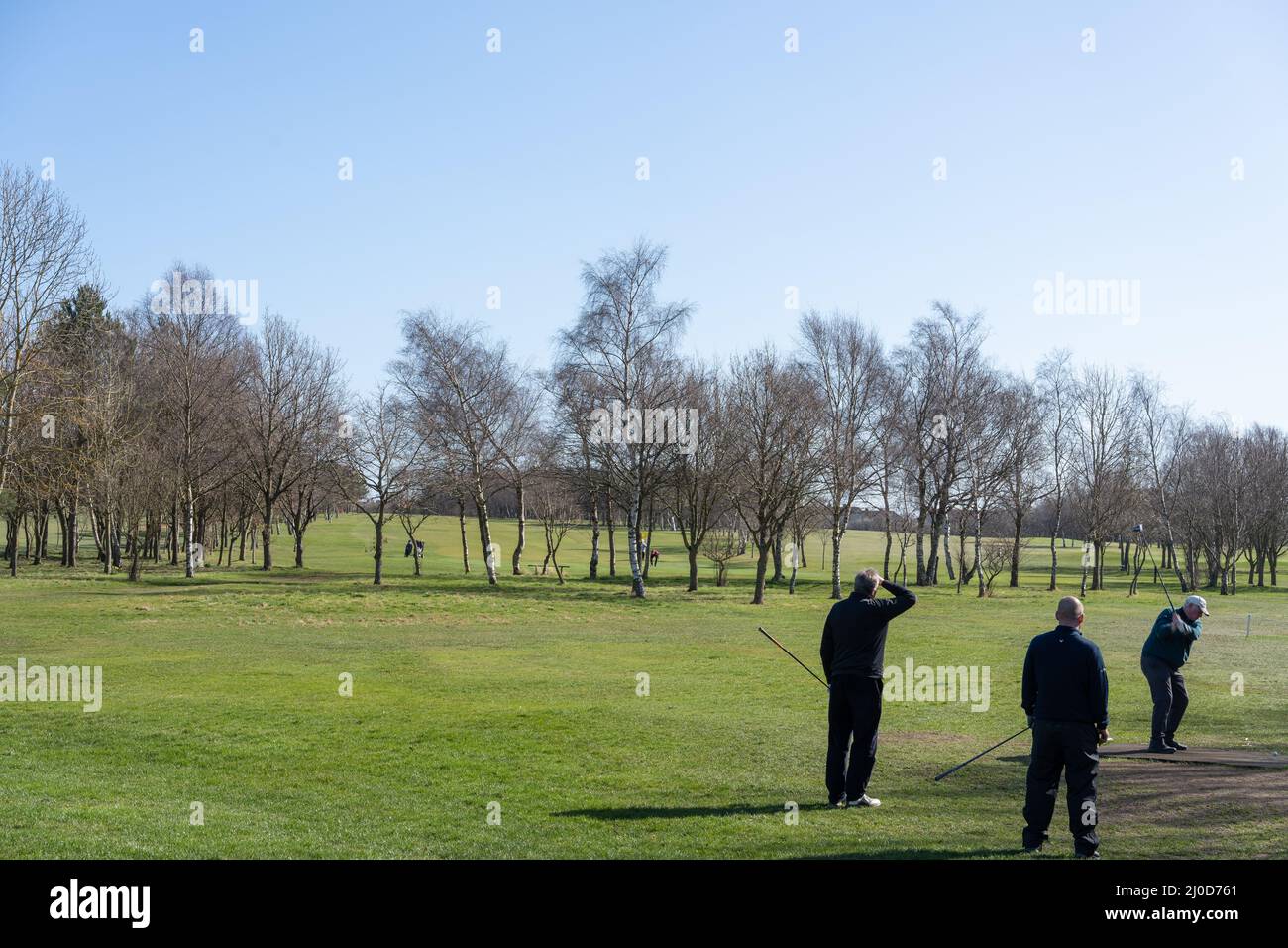 Un groupe de trois golfeurs masculins jouent au golf du club de golf de Gosforth, sous un ciel bleu clair. Banque D'Images