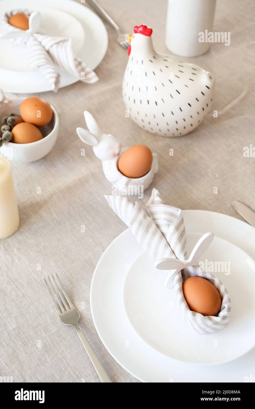 Concept de dîner de Pâques esthétique. Table de Pâques avec oeuf dans la  serviette de lapin de Pâques, poulet, vaisselle Photo Stock - Alamy