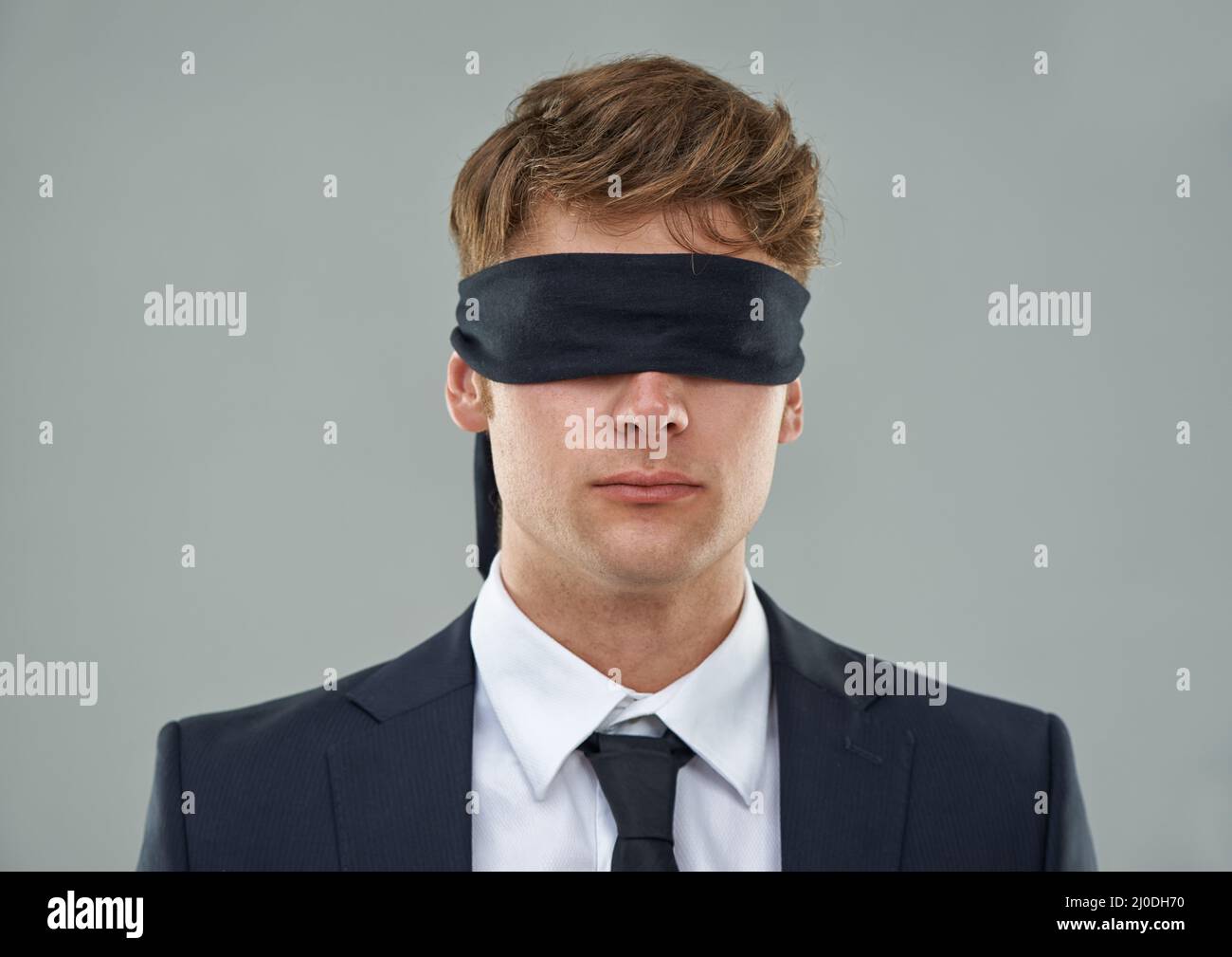 En entrant aveuglément dans la transaction Vue rognée d'un jeune homme d'affaires avec ses yeux bandés. Banque D'Images