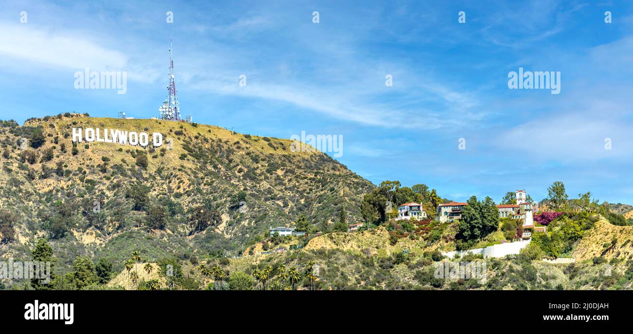 Le célèbre panneau blanc Hollywood dans les collines de Los Angeles, Californie avec des maisons riches à proximité encadrées par un beau ciel. Banque D'Images