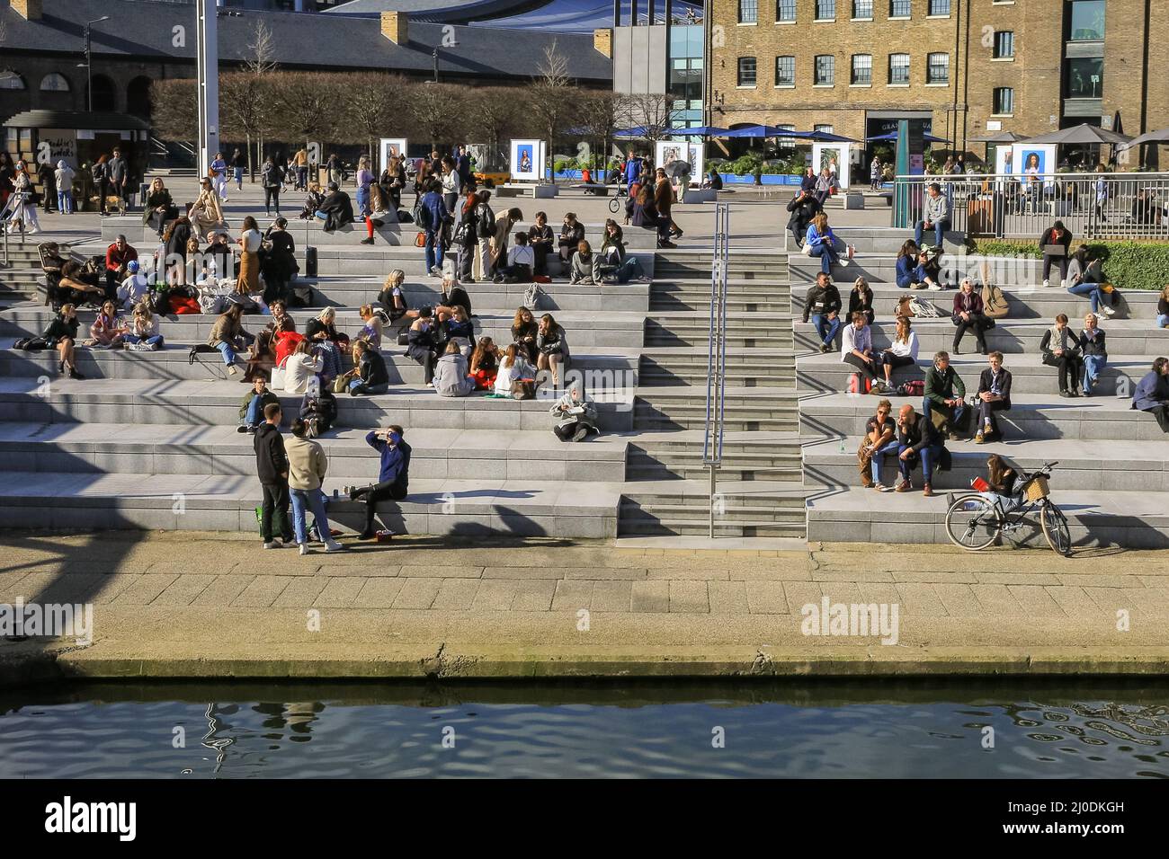 Londres, Royaume-Uni. 18th mars 2022. Les gens de la place Granary de Londres bronzer au bord du canal. La capitale a connu une journée bien ensoleillée avec des températures allant jusqu'à 17 degrés et un ciel bleu clair tout au long de la journée. Credit: Imagetraceur/Alamy Live News Banque D'Images