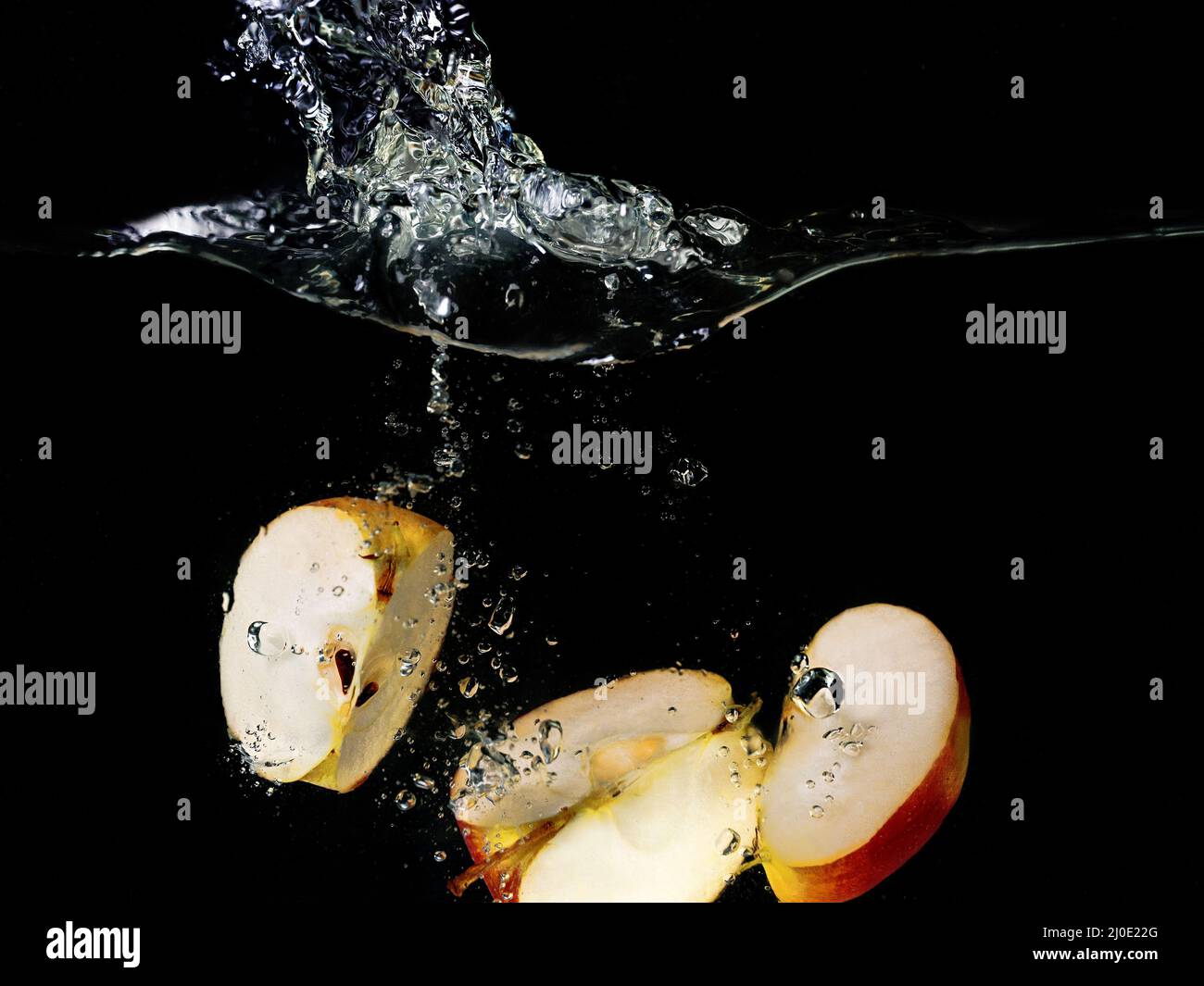 tranches de pommes tombant dans l'eau sur fond sombre. Vue sous l'eau. Cuisine, végétarien, cuisine à la maison concept Banque D'Images