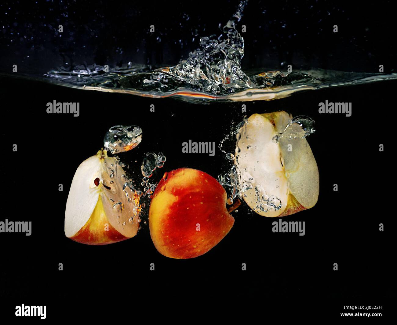 tranches de pommes tombant dans l'eau sur fond sombre. Vue sous l'eau. Cuisine, végétarien, cuisine à la maison concept Banque D'Images