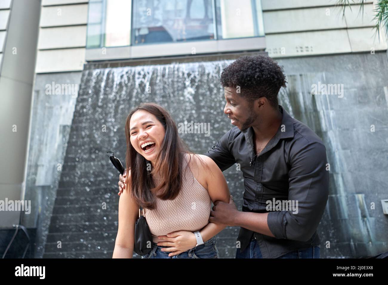 Femme asiatique qui rit à côté d'un ami africain dans un centre commercial Banque D'Images