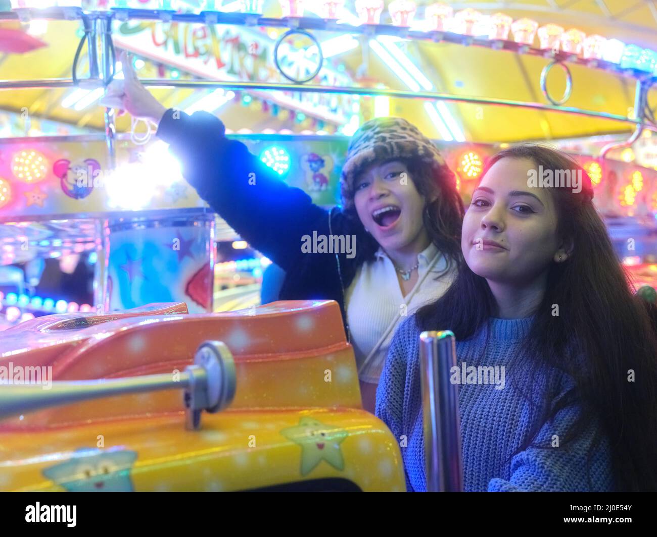 Deux femmes à l'intérieur d'une voiture de carrousel faisant le bonheur dans une foire de nuit Banque D'Images