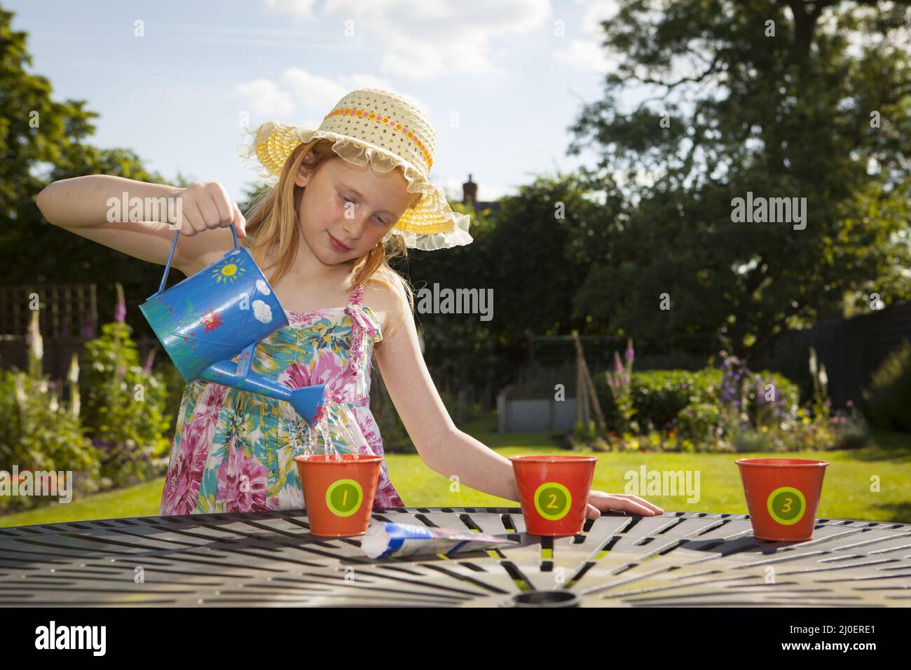 Avant l'adolescence caucasienne fille arrosoir pots de fleurs dans un jardin Banque D'Images