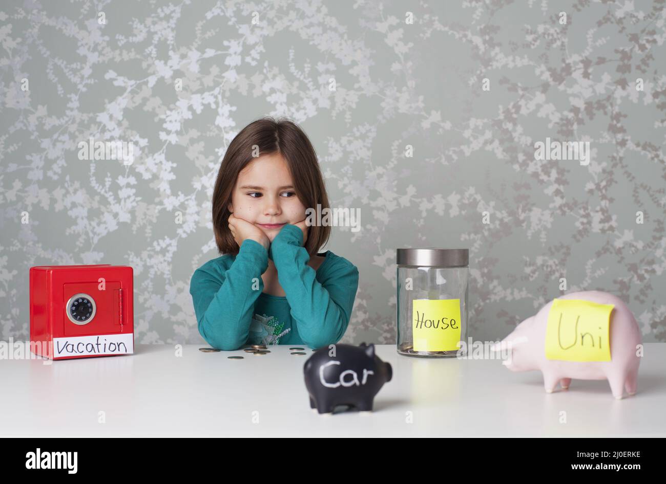 Fille entourée de tirelires et de caisses d'argent Banque D'Images