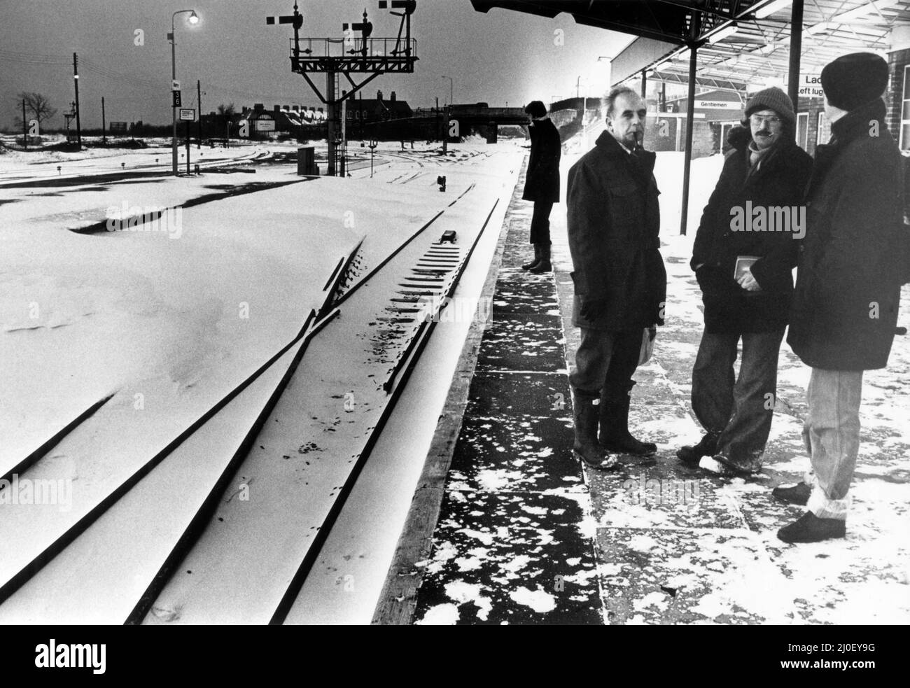 Les travailleurs du matin attendent un train à la gare Barry. La piste allant de Barry à Island Station a été bloquée par de la neige sur la piste, qui peut être vue à gauche de la photo, Barry gare, Vale of Glamourgan dans le sud du pays de Galles, 21st février 1978. Banque D'Images