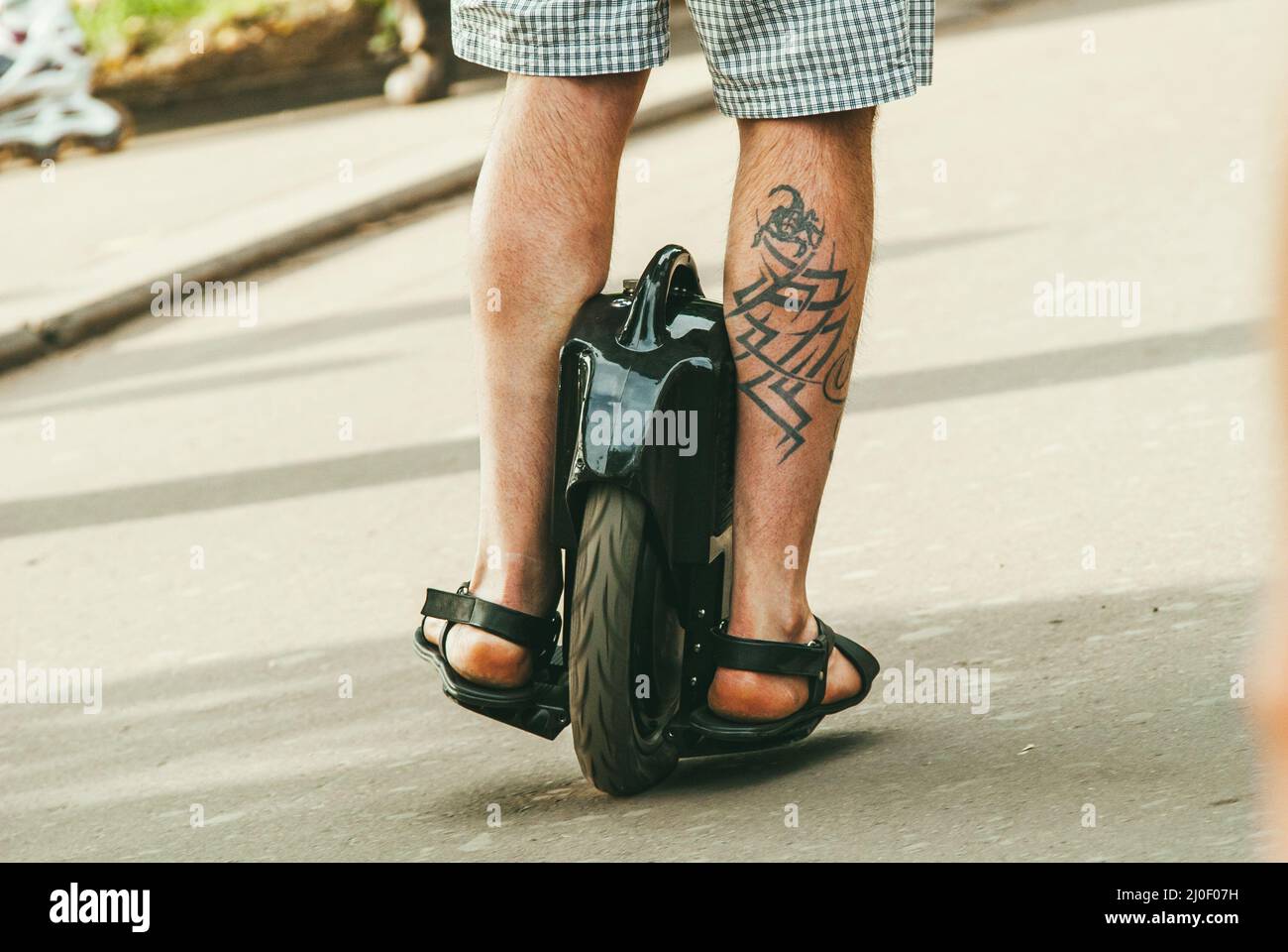 Moscou, Russie - 1er JUIN 2014. Un homme d'âge moyen sur un monocycle traverse le trottoir de la ville et il y a un tatouage sur la jambe Banque D'Images