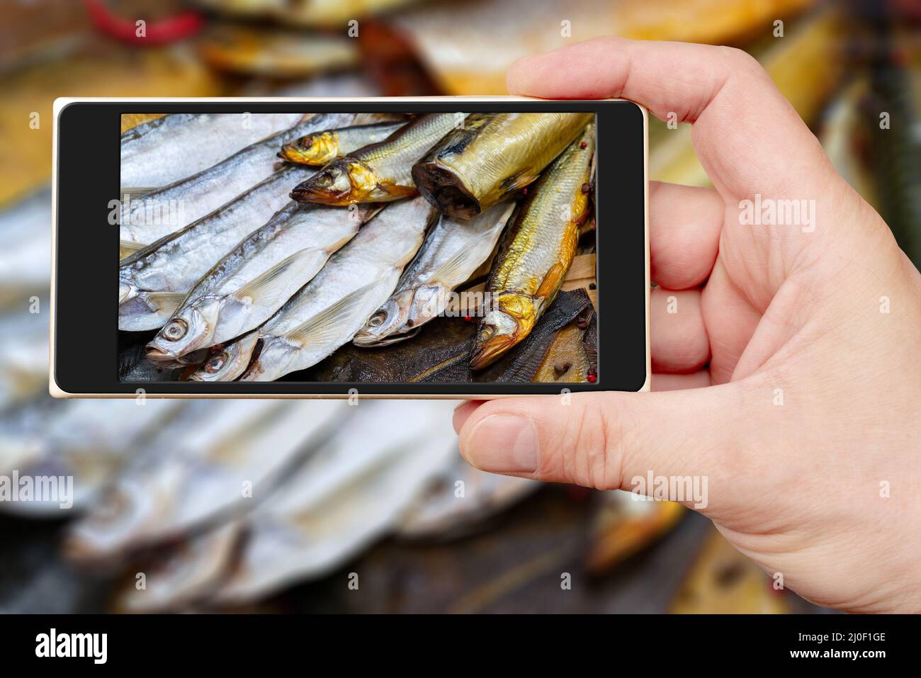 Poisson fumé sur l'écran du smartphone. Vente de fruits de mer. Poisson dans la fenêtre du magasin. Banque D'Images
