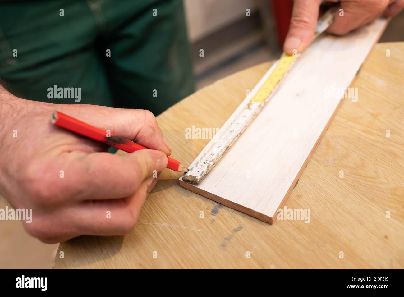 Un ouvrier de la construction mesure et se prépare à couper les carreaux de céramique Banque D'Images