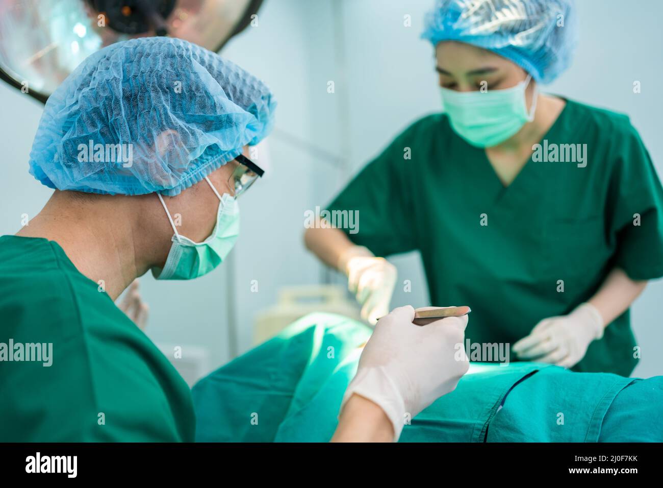 L'équipe de chirurgiens professionnels asiatiques effectuant la chirurgie dans la salle d'opération, le chirurgien, les assistants, et les infirmières effectuant la chirurgie sur un patient, voiture de santé Banque D'Images