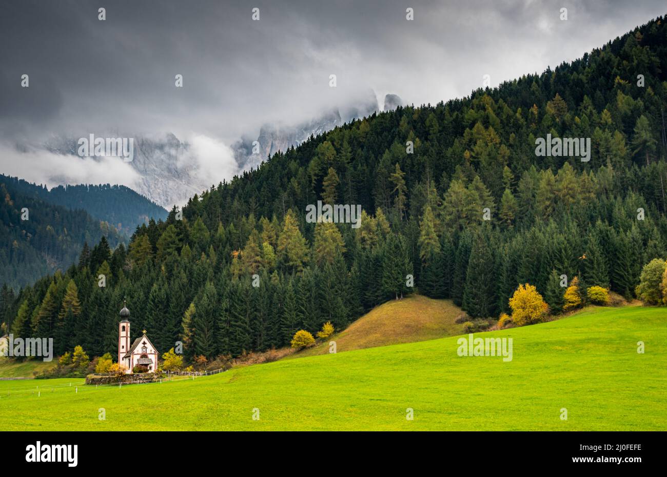 L'église de Saint John, Ranui, Chiesetta di san giovanni in Ranui Runes South Tyrol Italie, entourée de prairie verte, forêt Banque D'Images