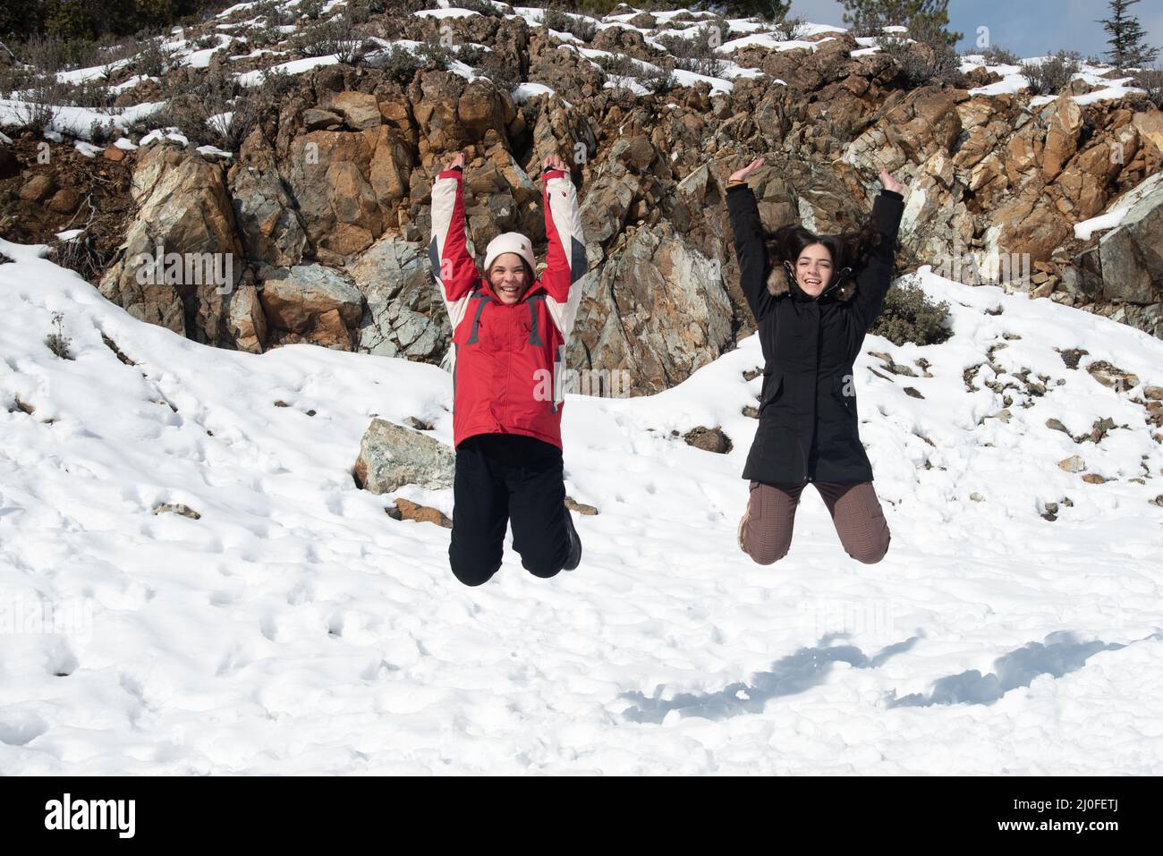 Deux jeunes filles adolescentes qui sautent avec plaisir dans la neige. Banque D'Images