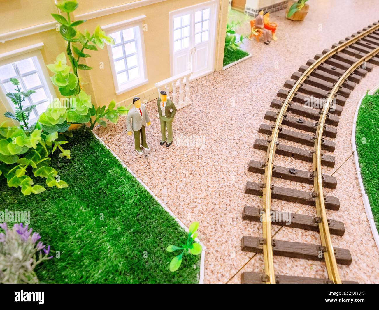 Chemin de fer jouet avec une pelouse, une maison miniature et de petits hommes Banque D'Images