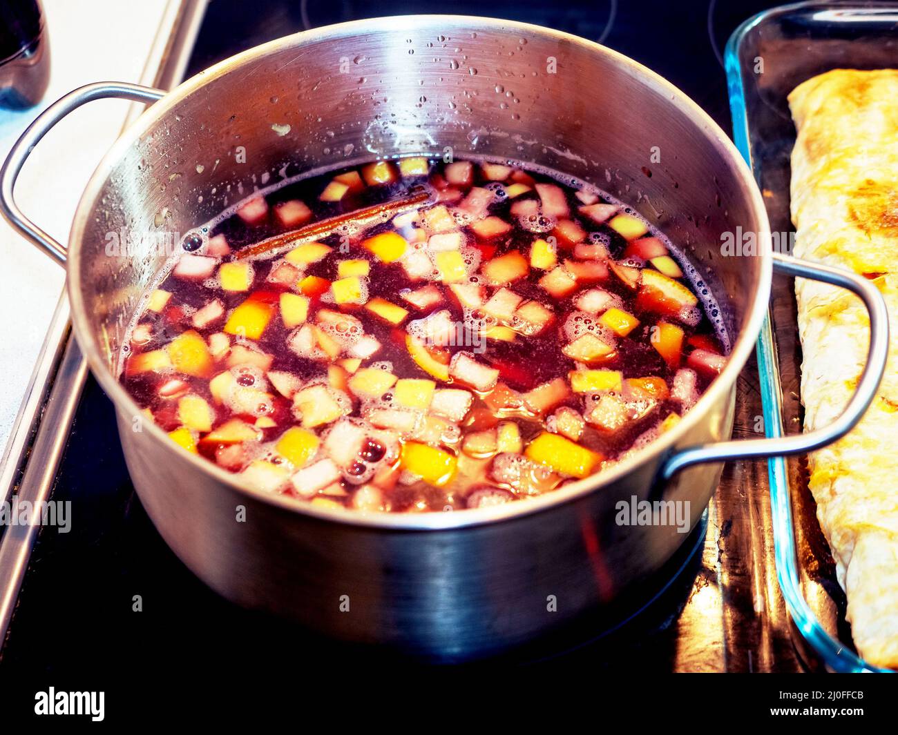 Le vin chaud avec beaucoup de fruits est cuit une poêle debout sur une cuisinière électrique Banque D'Images