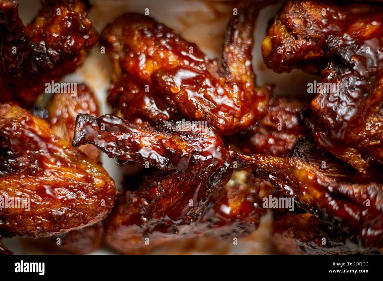 Gros plan sur les ailes de poulet dans une sauce barbecue épaisse. Servi sur un plat en fonte blanche Banque D'Images