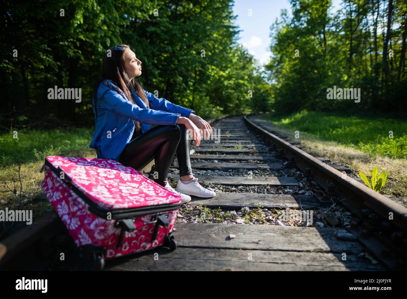 Lors de longs trajets à pied le long des voies, l'adolescent a décidé de s'asseoir et de se reposer directement sur la voie ferrée. Banque D'Images
