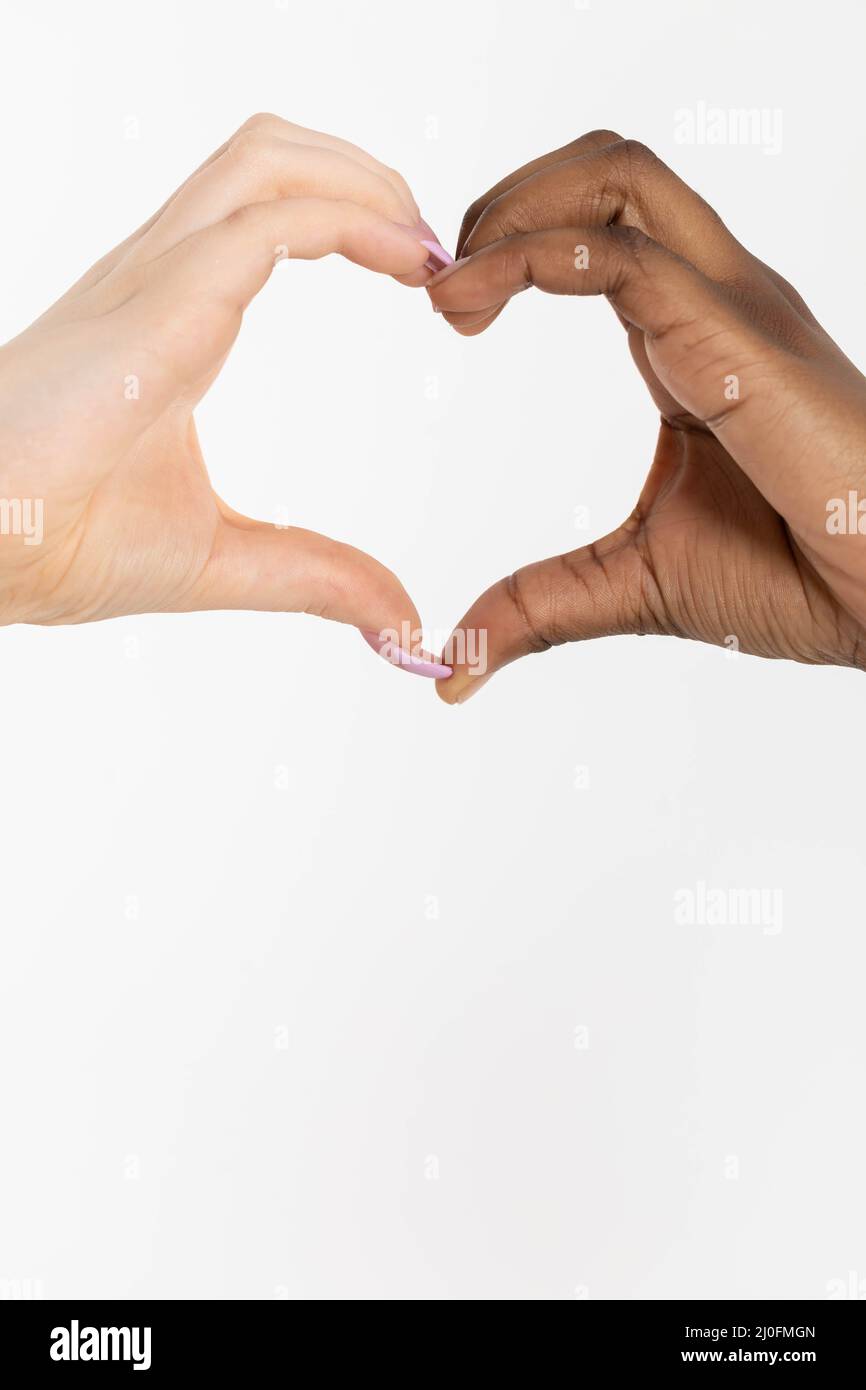 La forme d'un coeur composé de deux mains de races différentes, africaine et européenne. Ce coeur de l'amour est un message pour tous Banque D'Images