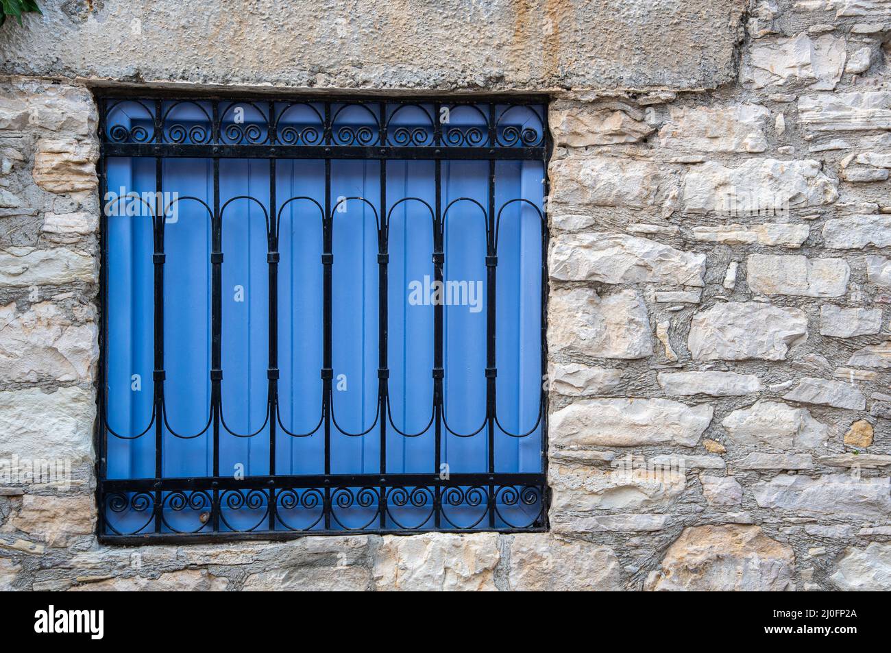 Fenêtre vintage en bois bleu avec un cadre de sécurité en métal sur un mur en brique Banque D'Images Fenêtre vintage en bois bleu avec un cadre de sécurité en métal sur un mur en brique Banque D'Images