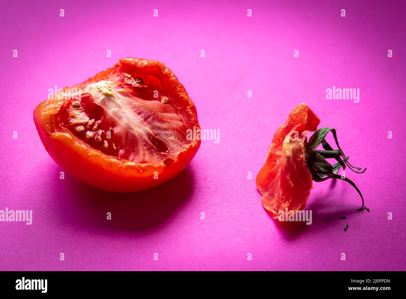 Tranche de légume de tomate rouge pourri isolée sur fond magenta Banque D'Images