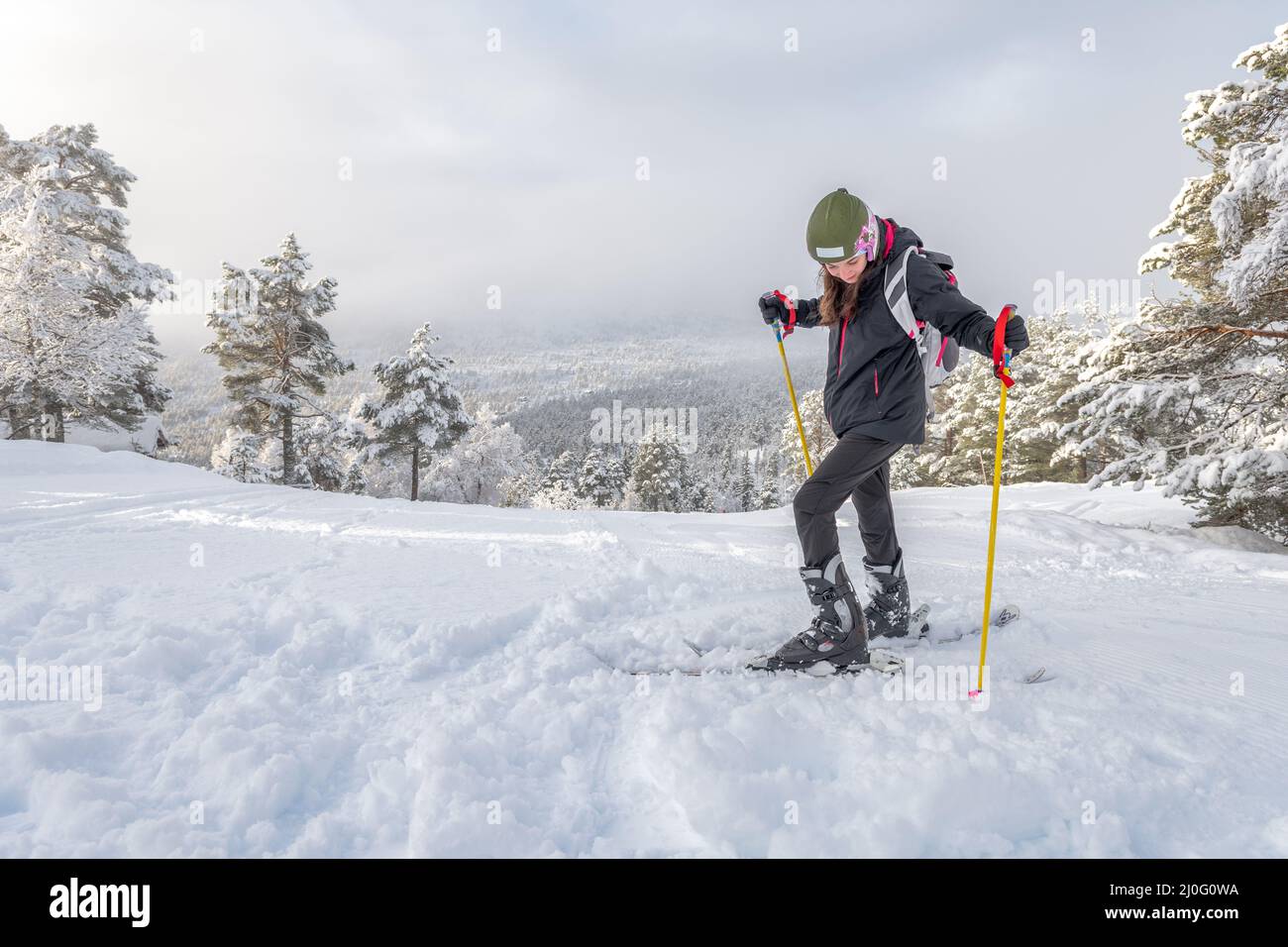 Femme aux cheveux bruns et vêtements de ski regardant vers le bas, fixant  et ajuste sa chaussure à son ski avant de skier en haut de la montagne à  stryn, non Photo