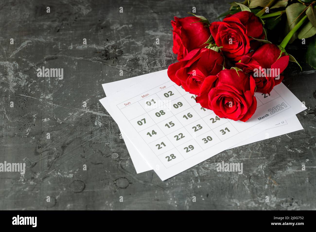 Concept international de la journée des Womans avec pages de calendrier de l'année 2021 de mars et roses rouges sur fond gris Banque D'Images