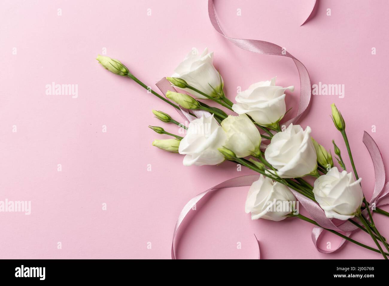 Concept international de la journée des femmes créé à partir de roses blanches et roses, ruban et perles sur un fond blanc rose clair Banque D'Images