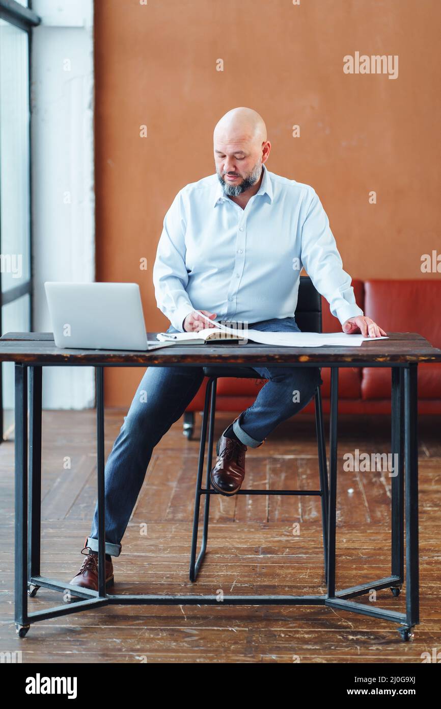 Homme d'affaires mature au bureau analysant des documents et faisant de la paperasse Banque D'Images