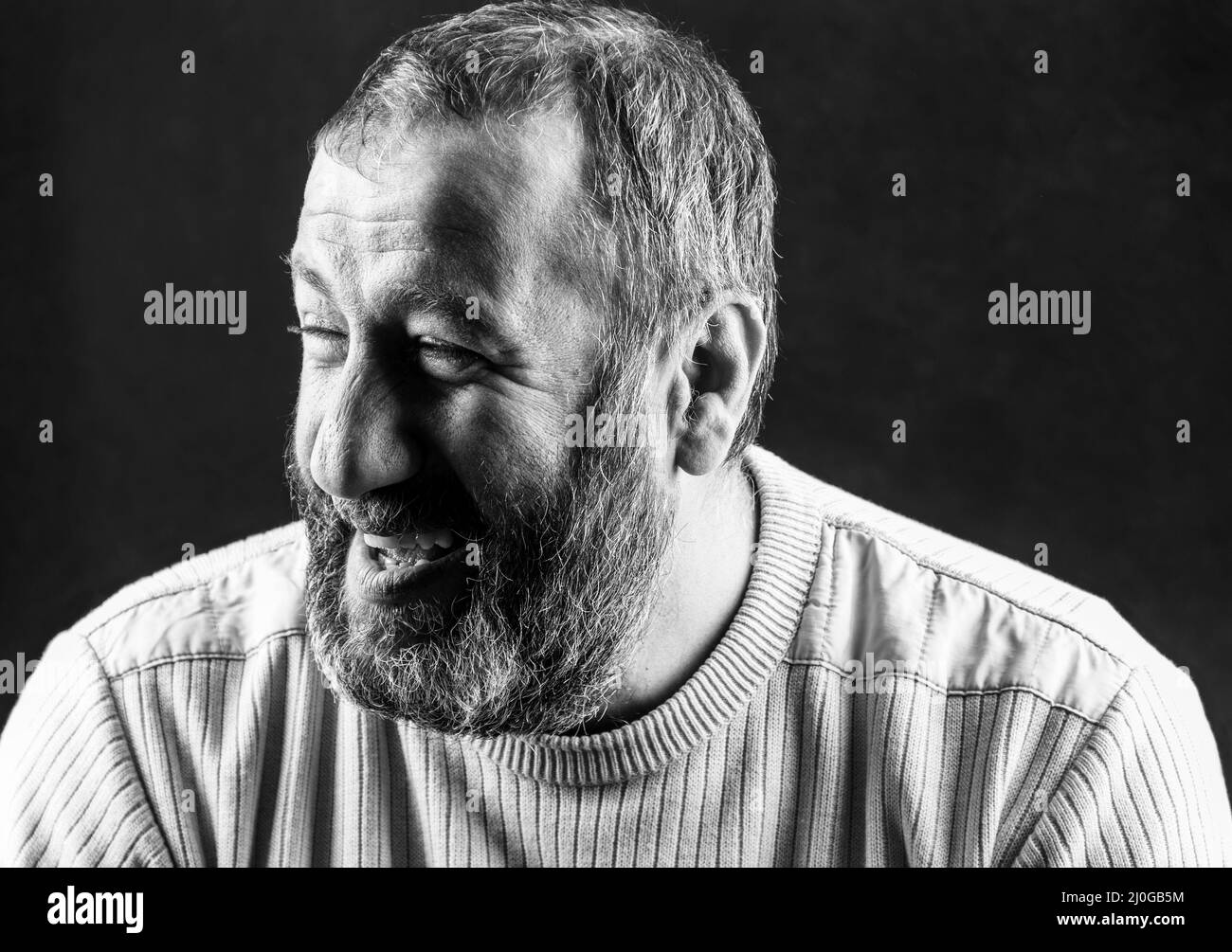 Portrait d'un arménien barbu gris souriant sur un fond gris foncé photo noir et blanc Banque D'Images