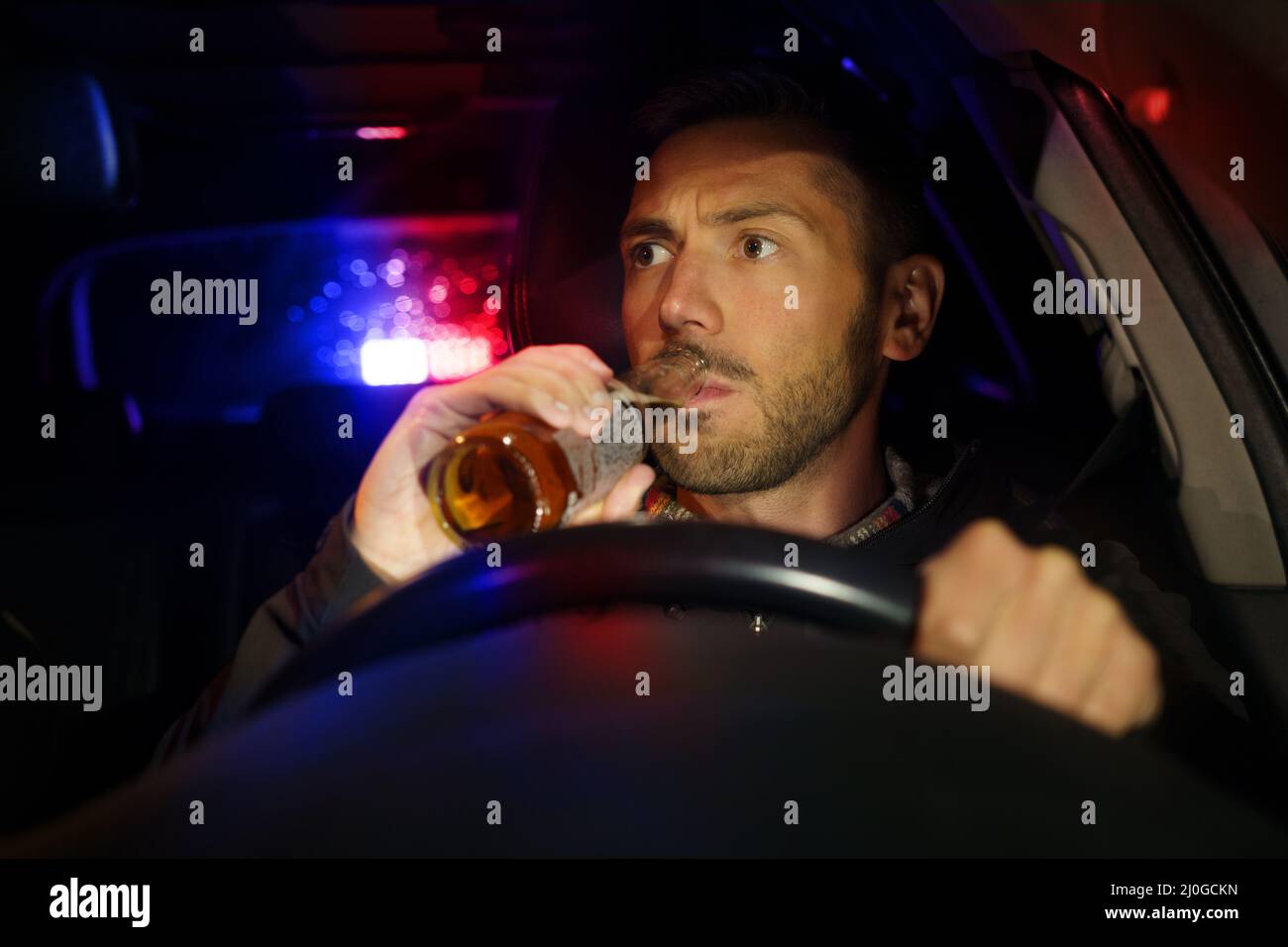 La police a arrêté la voiture avec un conducteur ivre à l'intérieur. Homme ivre qui boit de l'alcool en voiture. Conducteur sous influence d'alcool Banque D'Images