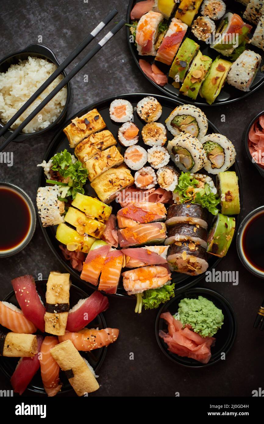 Assortiment de sushis servi sur fond sombre. Vue de dessus des fruits de mer, divers petits pains maki Banque D'Images