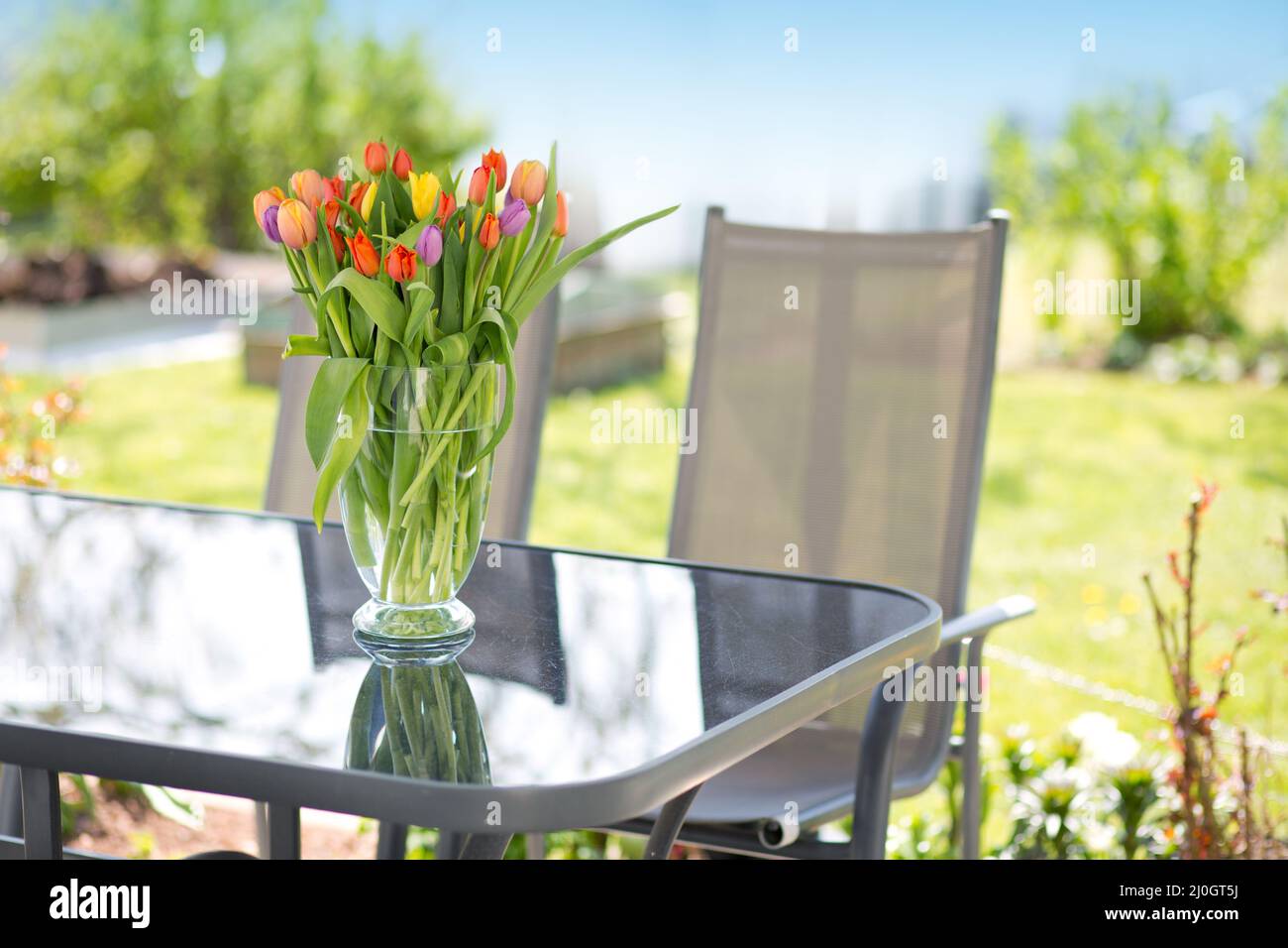 Beau bouquet de fleurs dans vase sur la table en verre. Banque D'Images