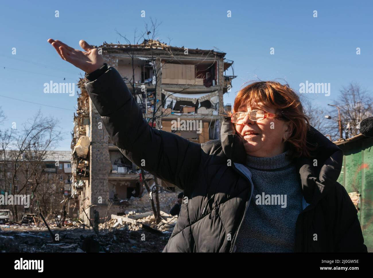 KIEV, UKRAINE - 18 mars 2022 : la guerre en Ukraine. Des bâtiments résidentiels endommagés à la suite d'un bombardement dans le district de Podilskyi à Kiev. Une femme sans domicile parle d'une explosion de construction d'appartements Banque D'Images