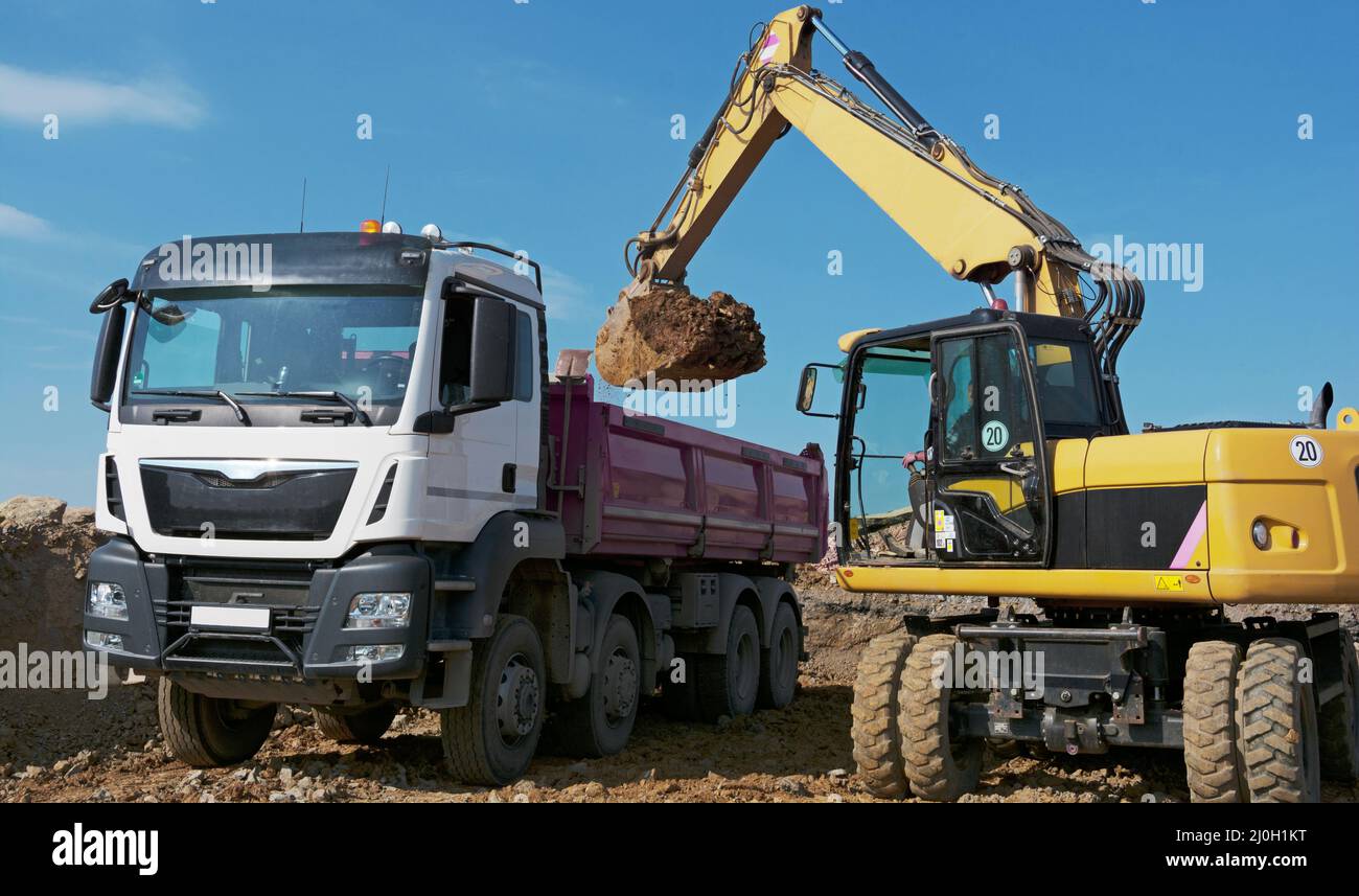 La pelle hydraulique charge les camions avec l'excavation Banque D'Images