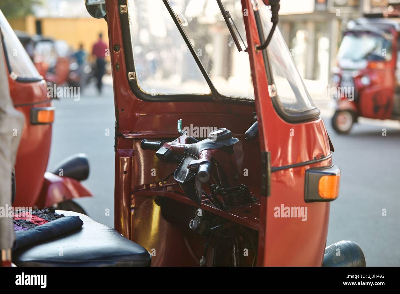 Tuk tuk rouge garé contre la rue animée. Populaire moto à trois roues au Sri Lanka. Banque D'Images