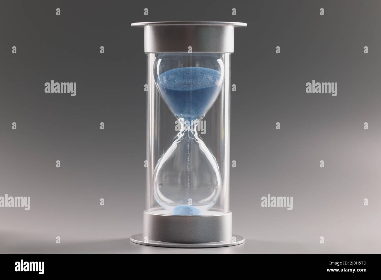 Mesurer le temps de passage, le compte à rebours, le sable bleu passant à travers les ampoules du sablier Banque D'Images