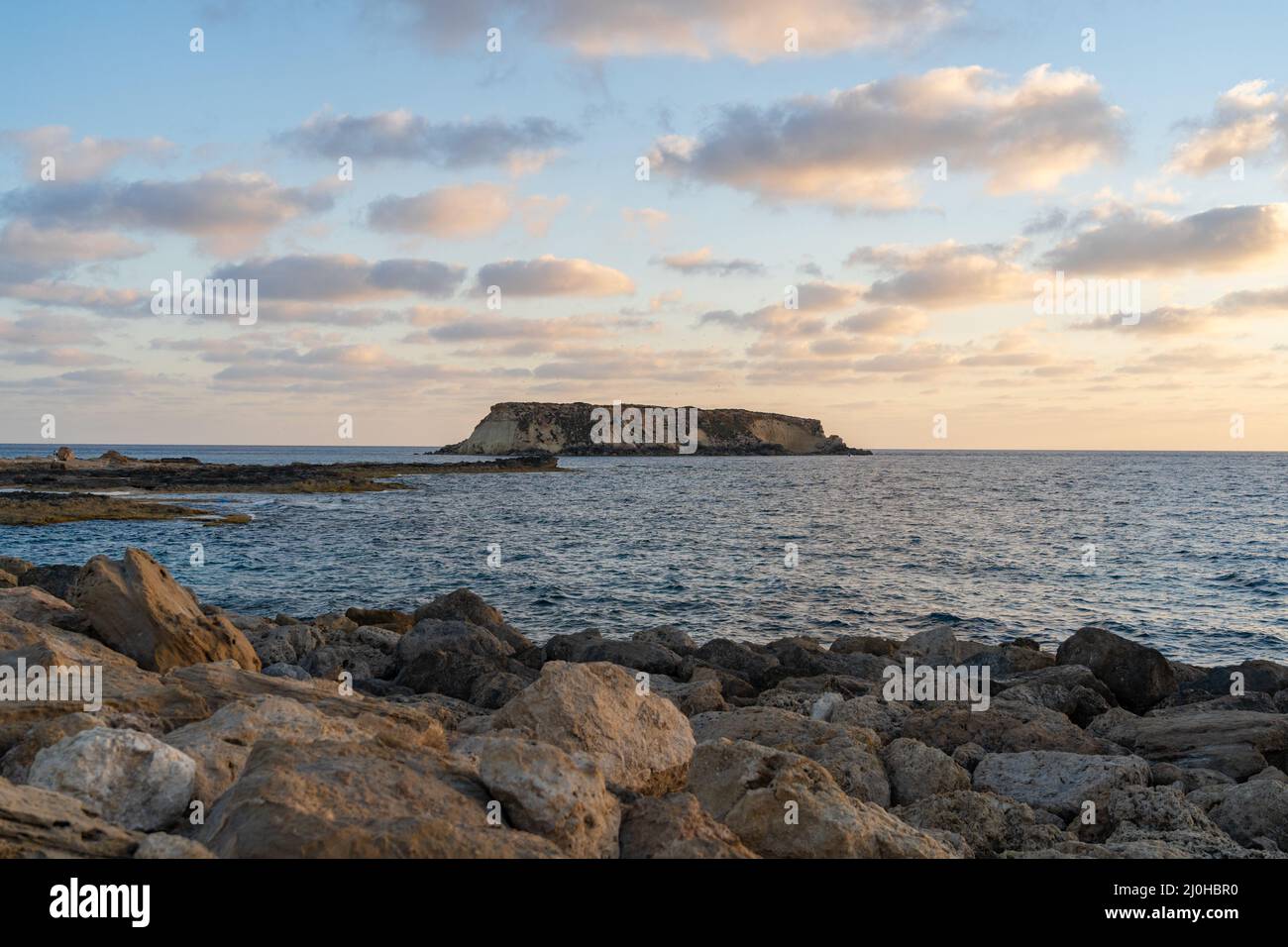 Côte rocheuse d'Agios Georgios Chypre. Vue sur l'île de Yeronisos. Coucher de soleil sur le port d'Agios Georgios Pegeias à Paphos, Chypre. T Banque D'Images