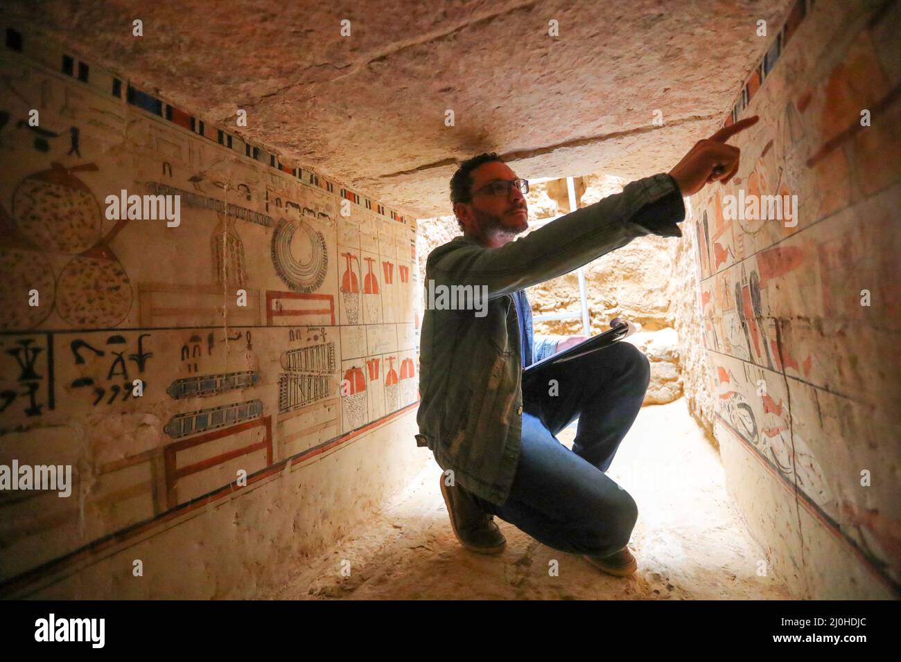 (220319) -- LE CAIRE, le 19 mars 2022 (Xinhua) -- un archéologue présente la peinture murale dans une ancienne tombe découverte sur les sites archéologiques de Saqqara, au sud-ouest du Caire, en Égypte, le 19 mars 2022. Le ministère égyptien du Tourisme et des Antiquités a annoncé jeudi la découverte de cinq tombes anciennes de 4 000 ans dans les sites archéologiques de Saqqara, au sud-ouest du Caire. Les tombes contiennent des découvertes et des objets datant de la fin de l'ancien Royaume s'étendant de 2686 BC à 2181 BC et le début de la première période intermédiaire s'étendant de 2181 BC à 2055 BC. ALLER AVEC 'Egypt dis Banque D'Images