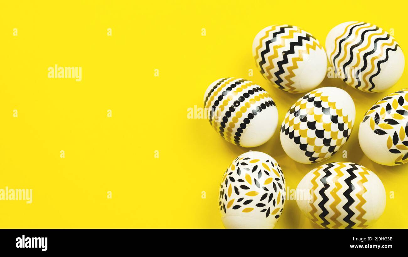 Concept de pâques minimal. Œufs de Pâques dorés avec motif géométrique sur fond jaune. Bannière Web. Banque D'Images